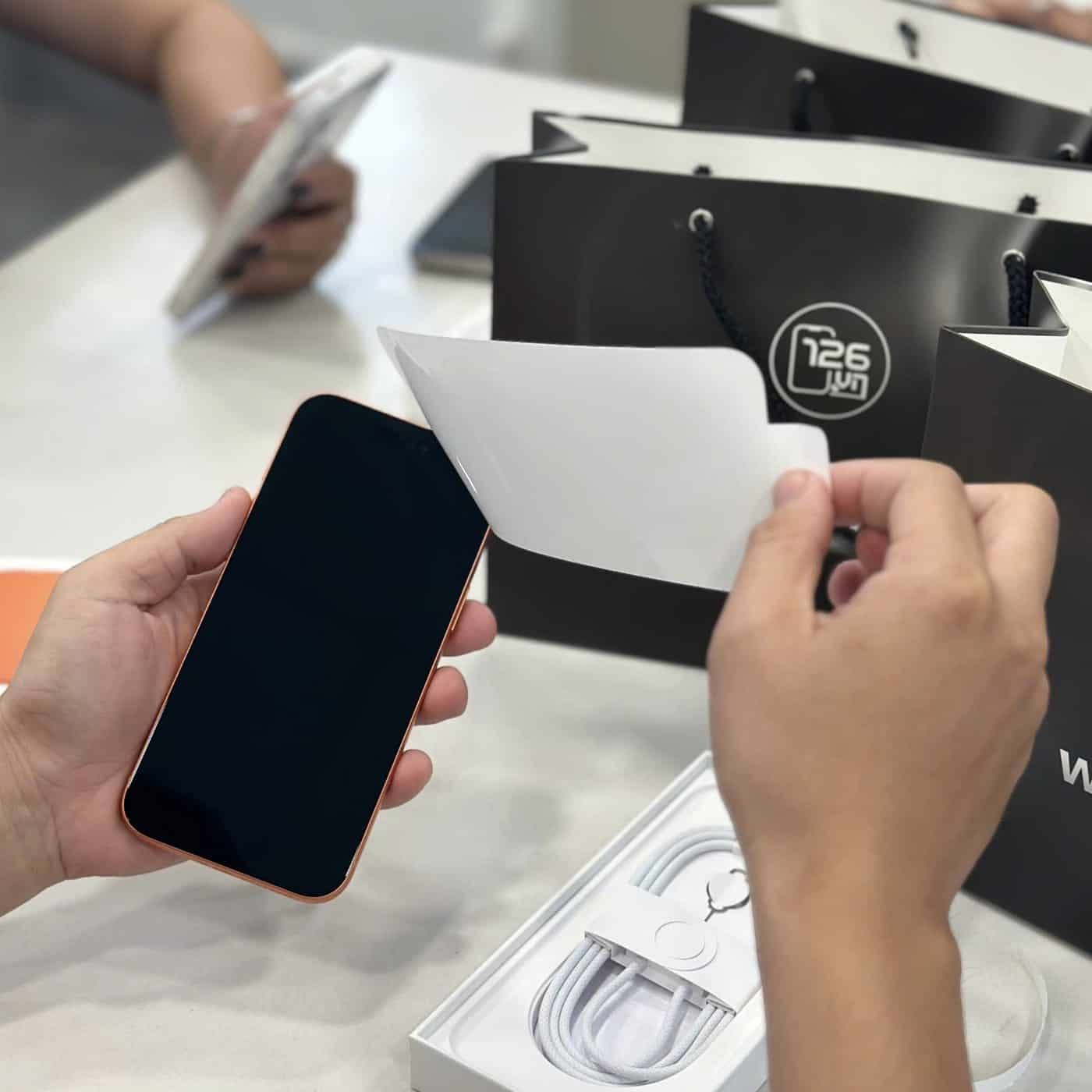 Nhân viên 126.vn dán màn hình tặng kèm cho khách mua iPhone mới