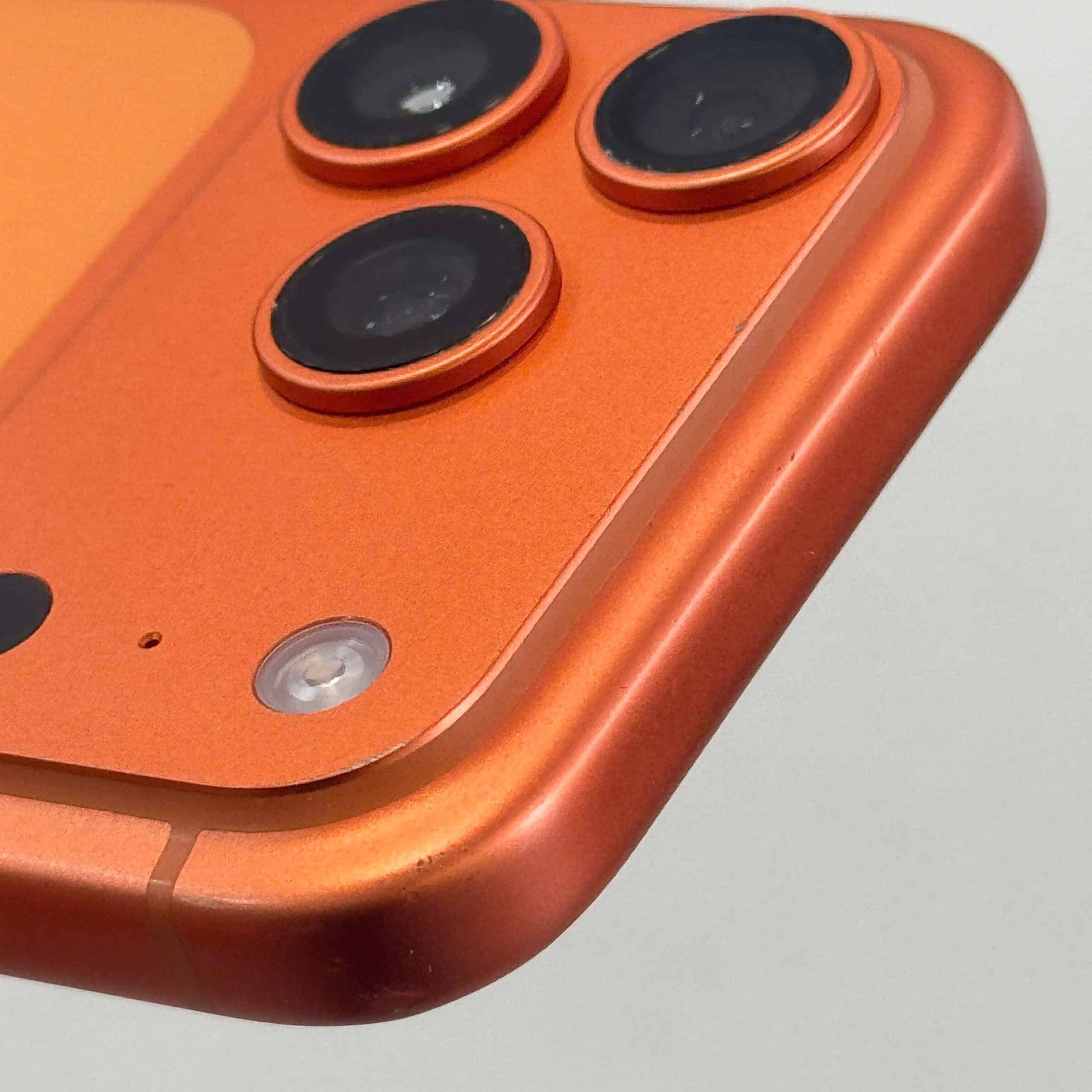 Cận cảnh cụm ba camera và mặt lưng một chiếc iPhone cũ màu cam
