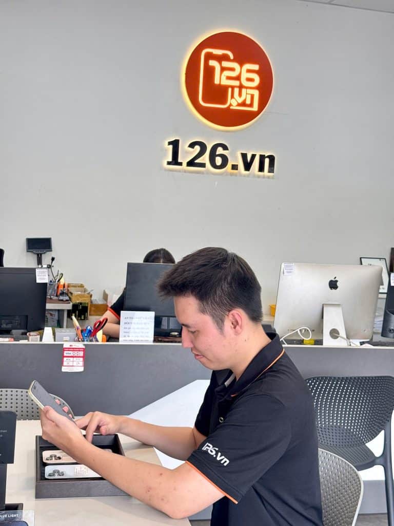 Nhân viên 126 kiểm tra iPhone cũ tại quầy trong cửa hàng