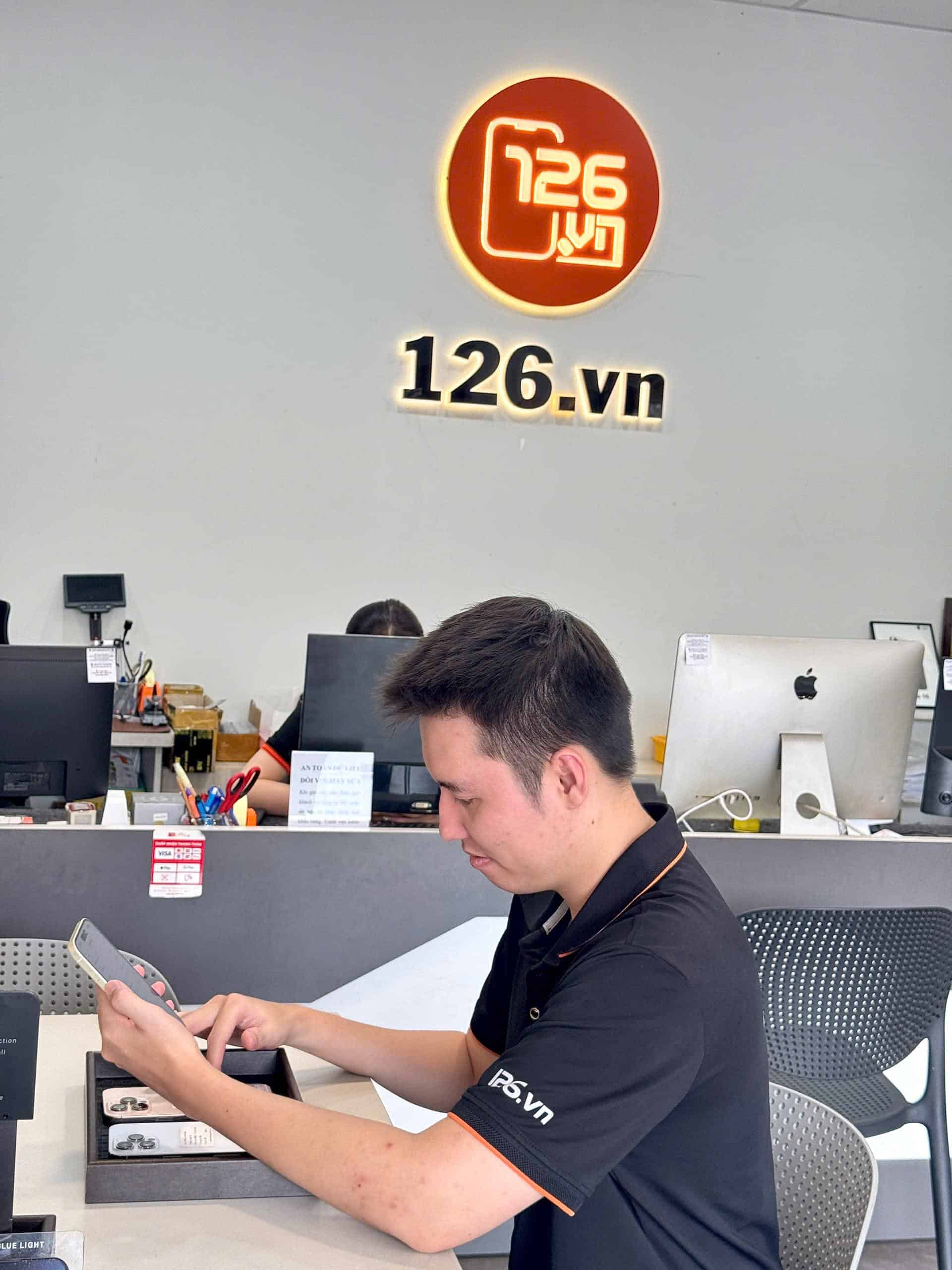 Nhân viên 126 kiểm tra iPhone cũ tại quầy trong cửa hàng